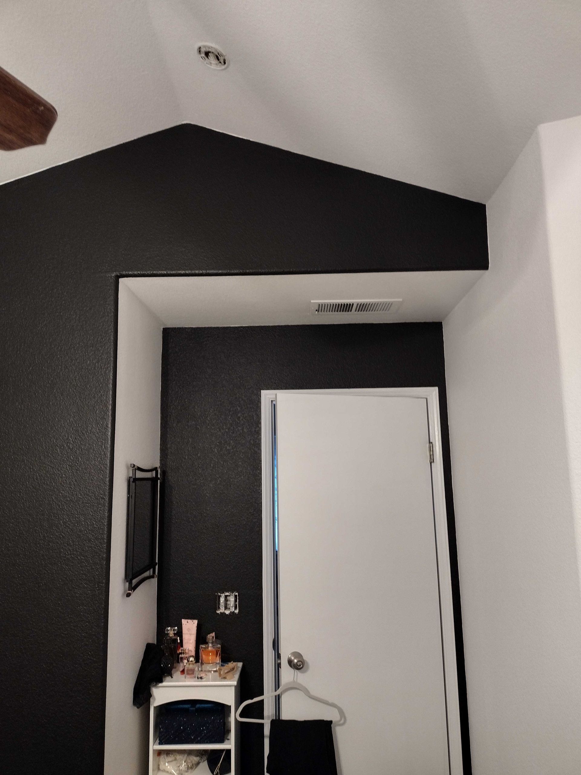 A corner room features textured black accent walls and a white door