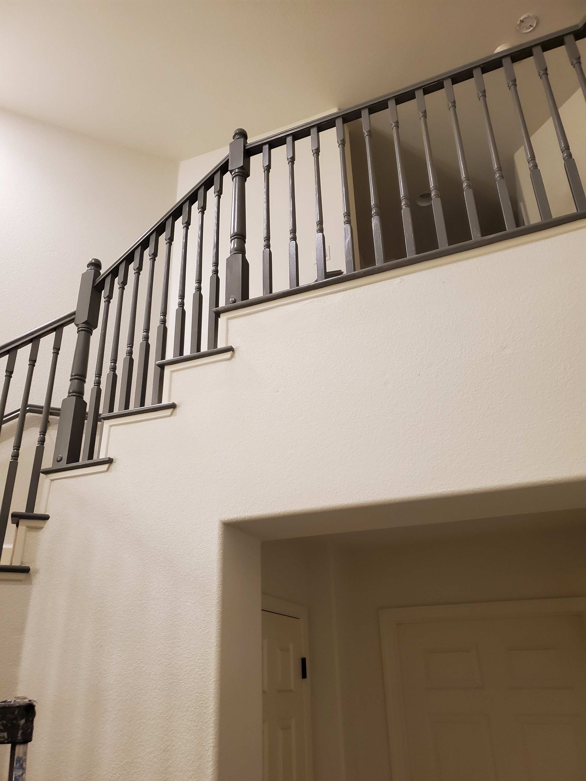 Indoor staircase with dark wooden railing and white walls above a doorway