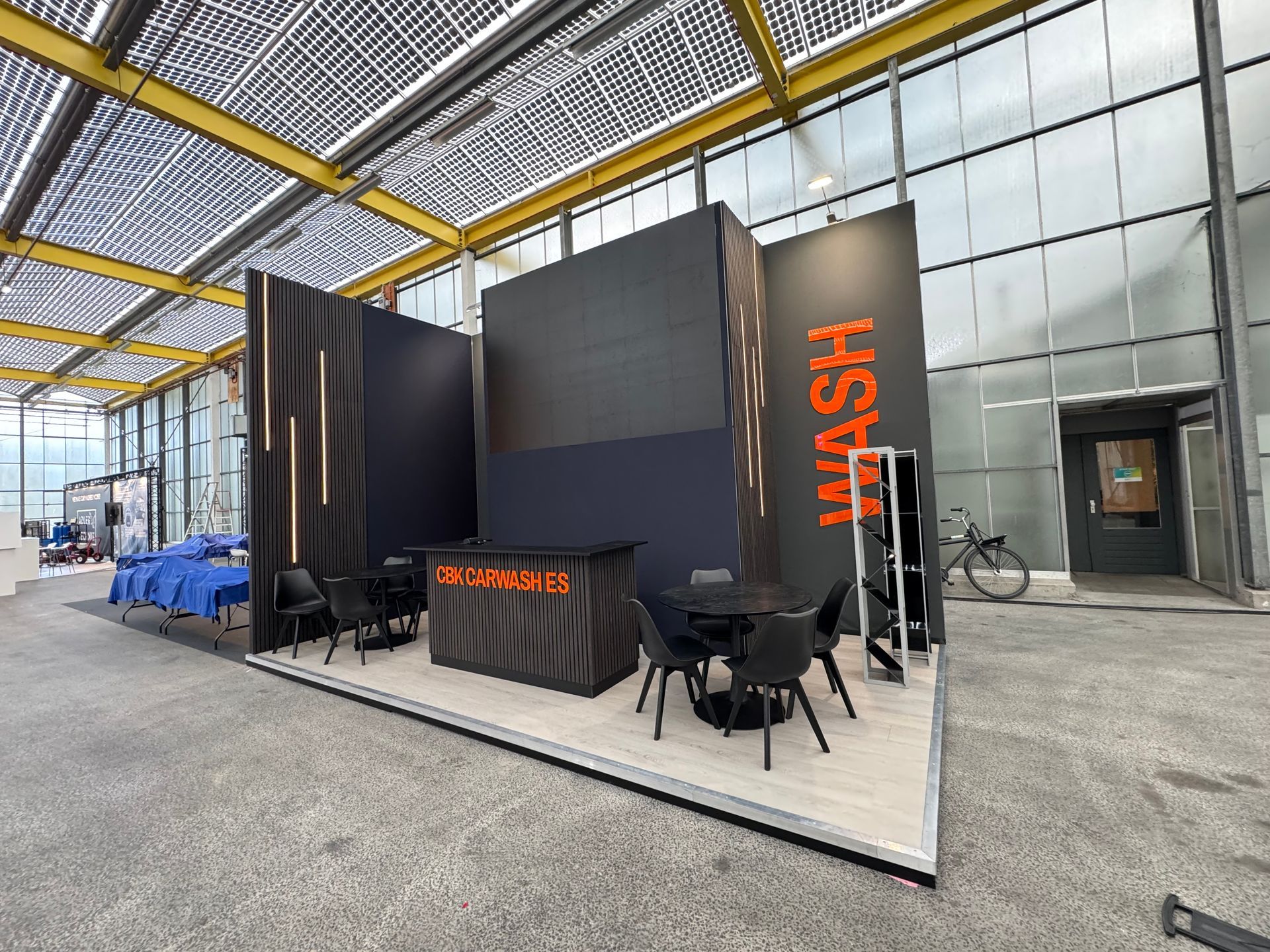 A modern dark gray exhibition booth with bematrix frames and seg graphic backdrop