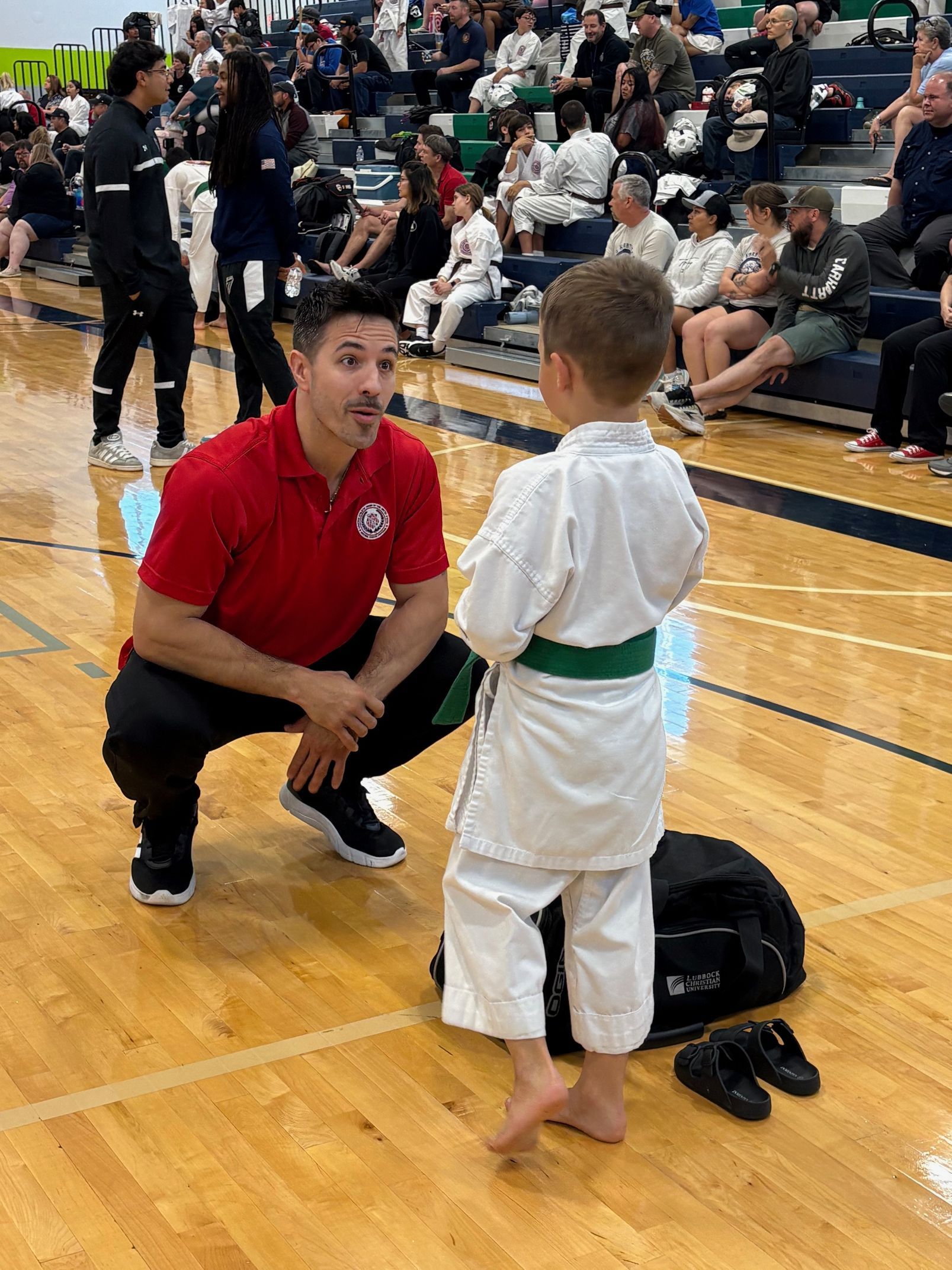 A little girl in a karate uniform is holding a wooden stick.