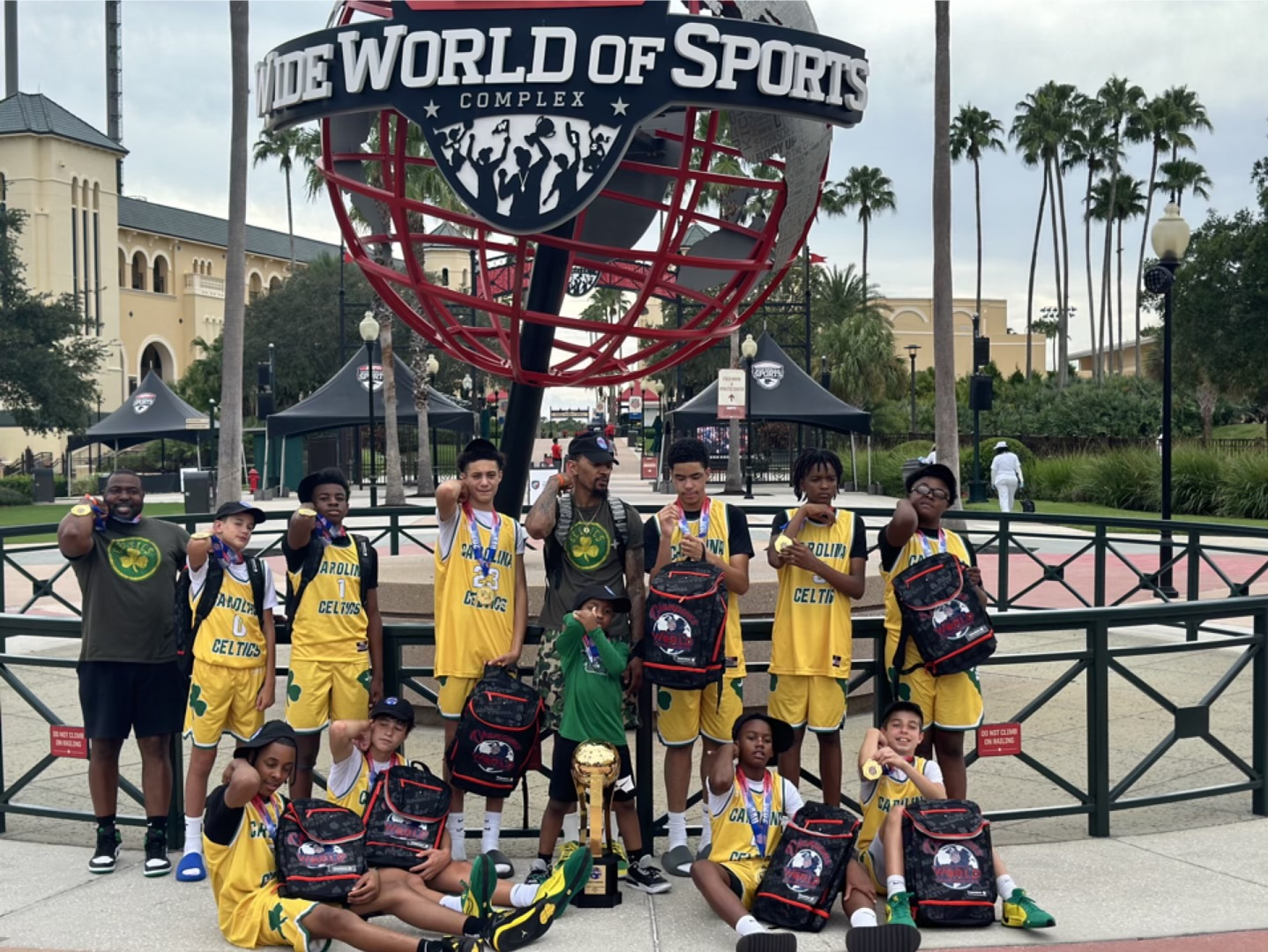 A group of young boys are posing for a picture in front of a world of sports sign.