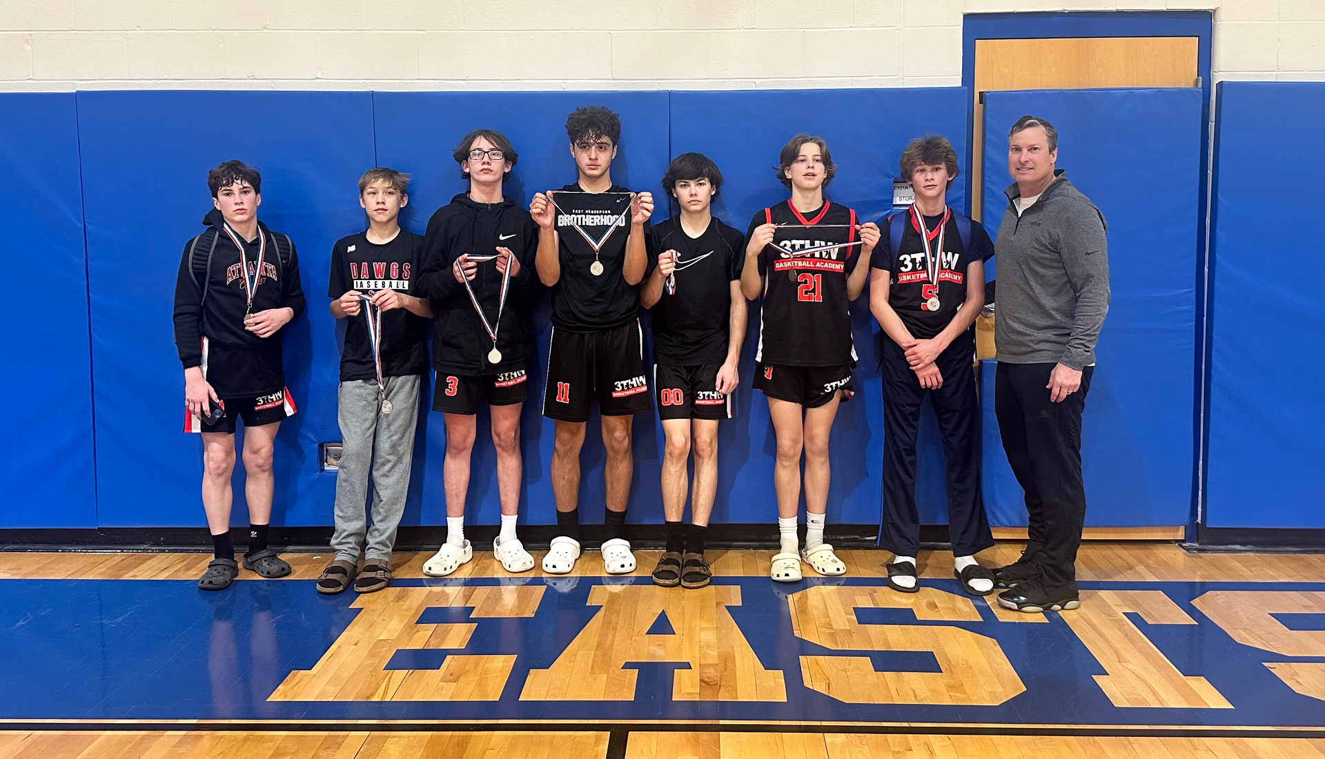 A group of young men are posing for a picture in a gym.