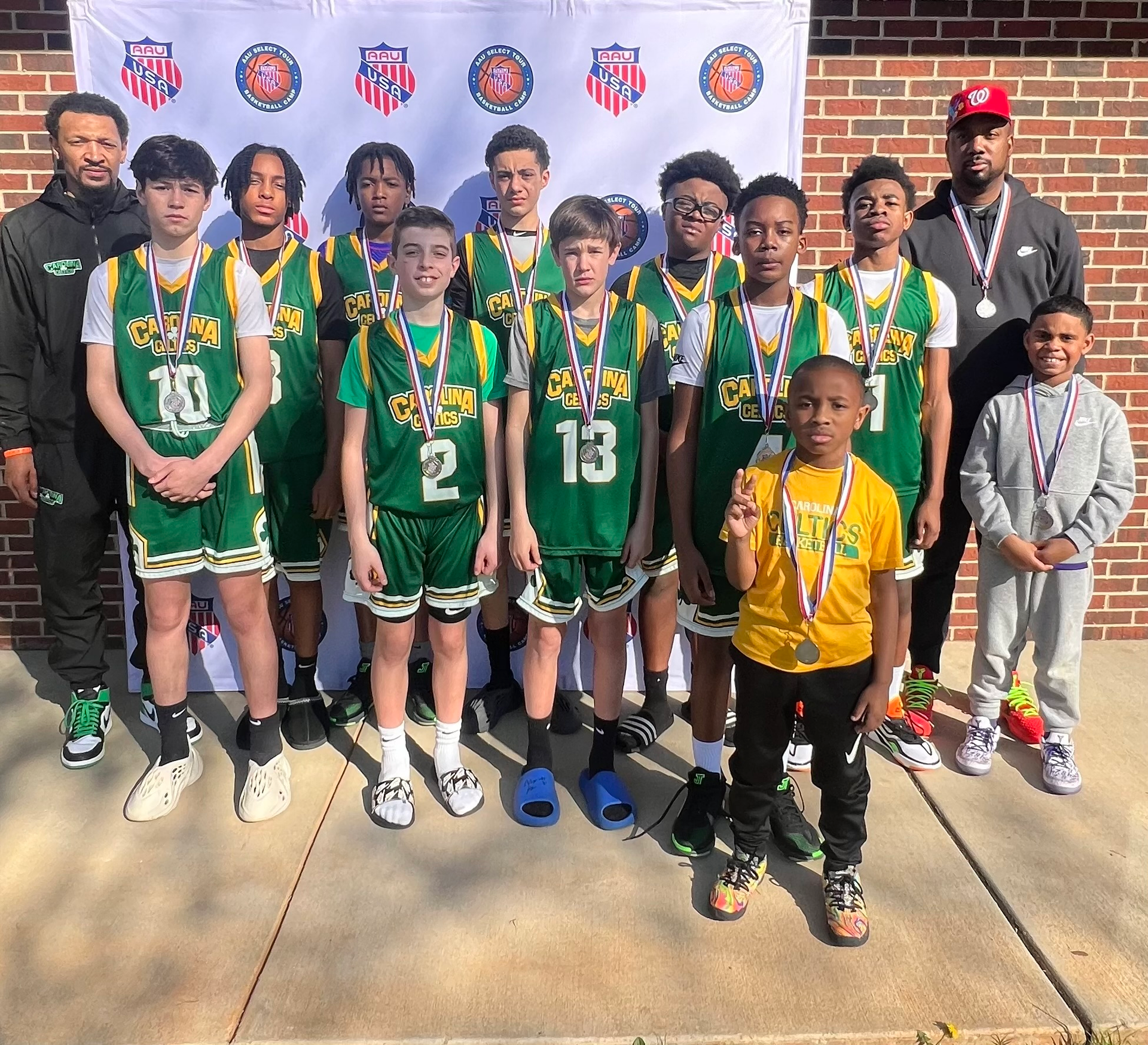 A group of young boys wearing green jerseys with the number 2 and 13 on them