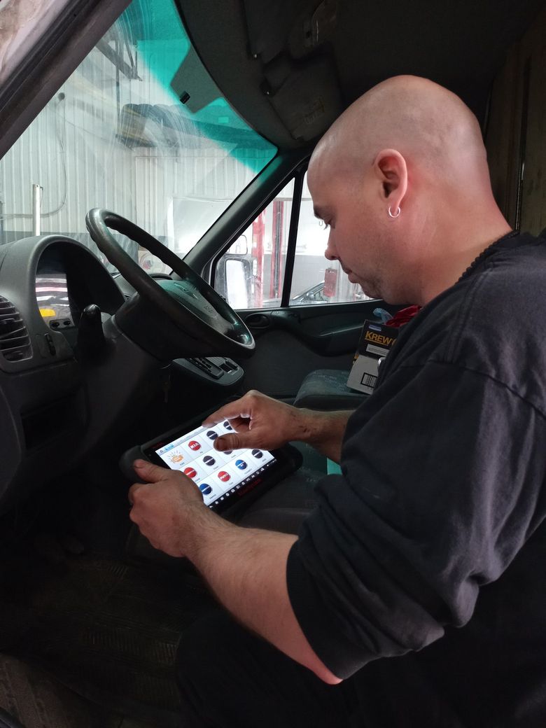 Une personne à bord d'un véhicule utilise une tablette en étant assise au volant.