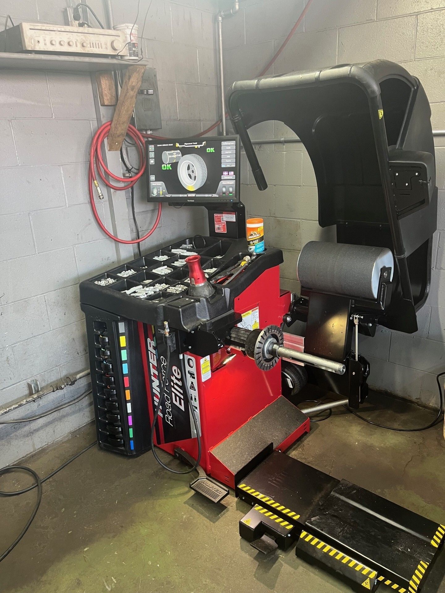 Machine industrielle dans un atelier, avec commandes rouges et noires, tuyaux et un grand panneau métallique incurvé.