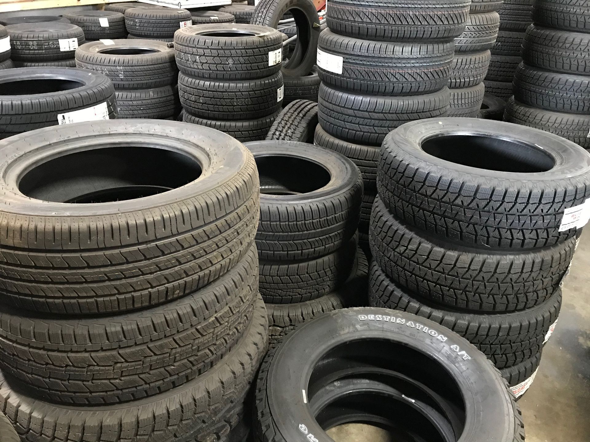 A bunch of tires are stacked on top of each other in a warehouse.