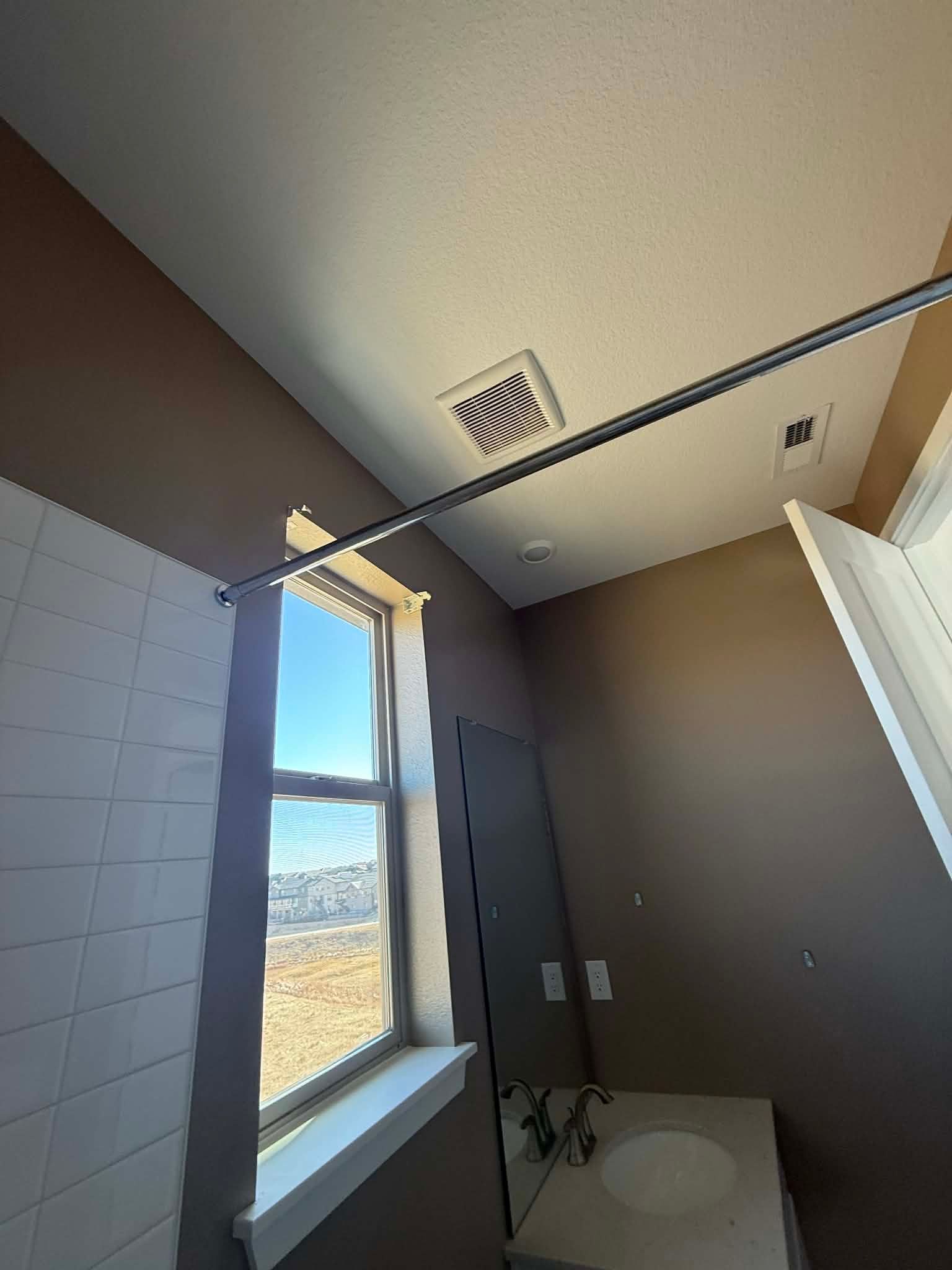 Small bathroom with a window, shower rod, white tile, and a toilet visible in the corner.