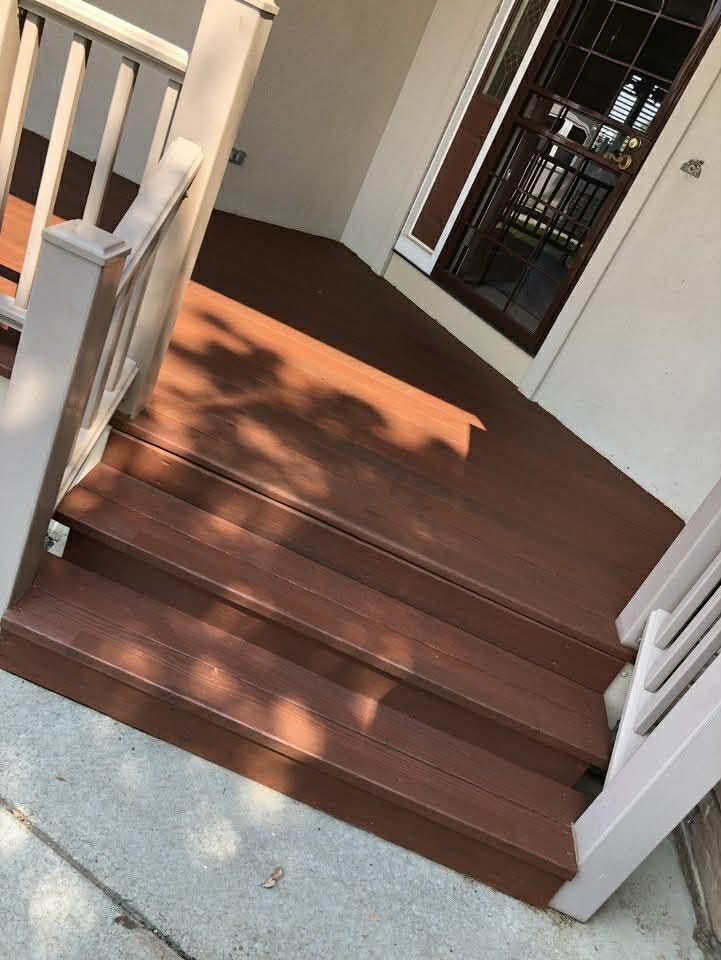 Brown wooden porch steps with white railings in bright sunlight