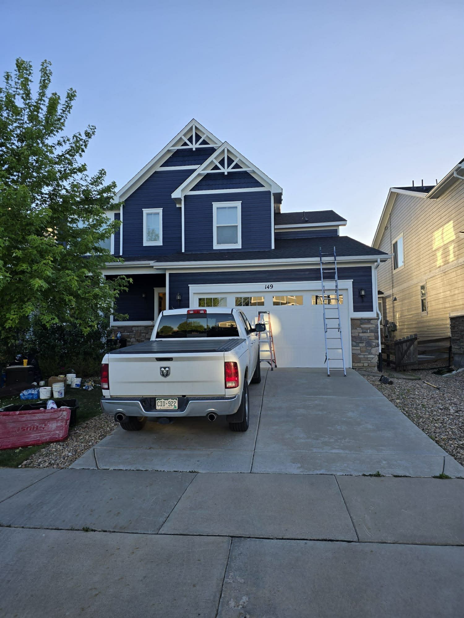 Blue two-story house with a white pickup truck parked in the driveway at dusk