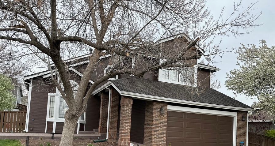 Brick suburban house with attached garage and leafless tree in front yard