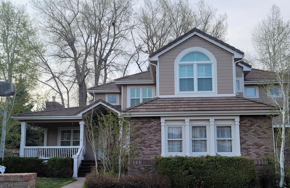 Two-story brick house with a covered porch and large arched windows amid bare trees
