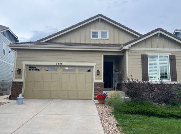 Front view of a beige suburban house with a two-car garage, white trim, and a small front lawn.