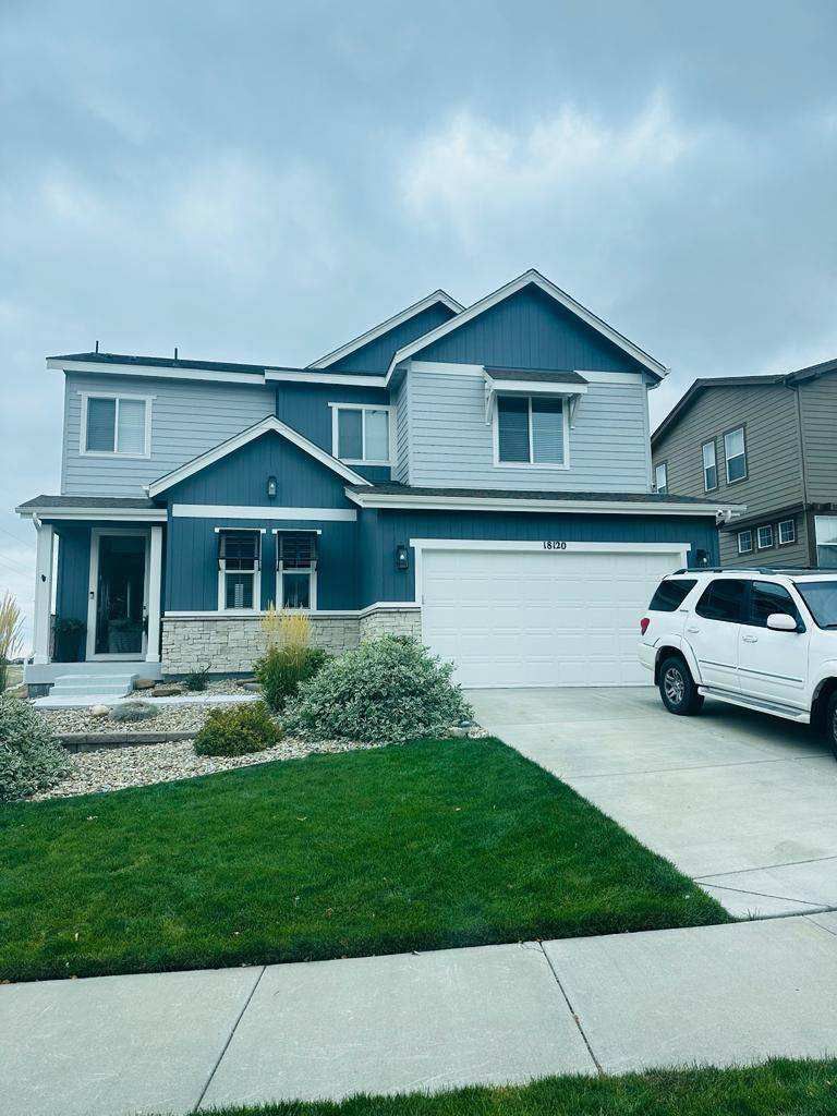 Blue two-story suburban house with white trim, garage, driveway, and a white SUV parked outside