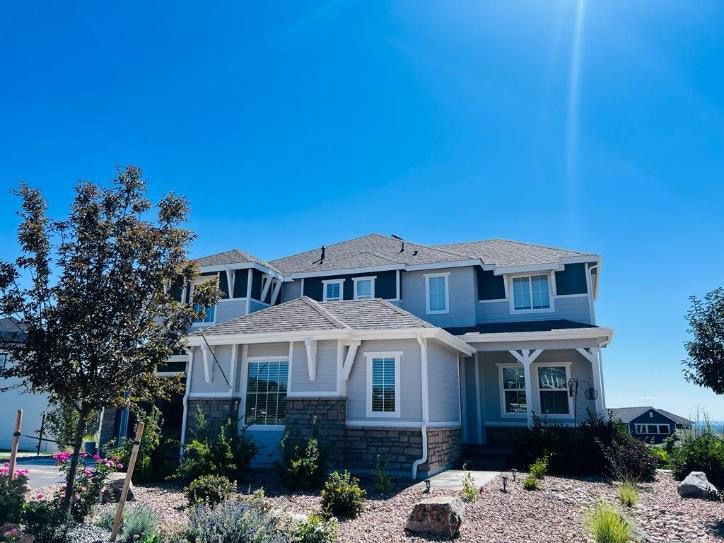 Two-story blue house with white trim and a front porch under a bright blue sky