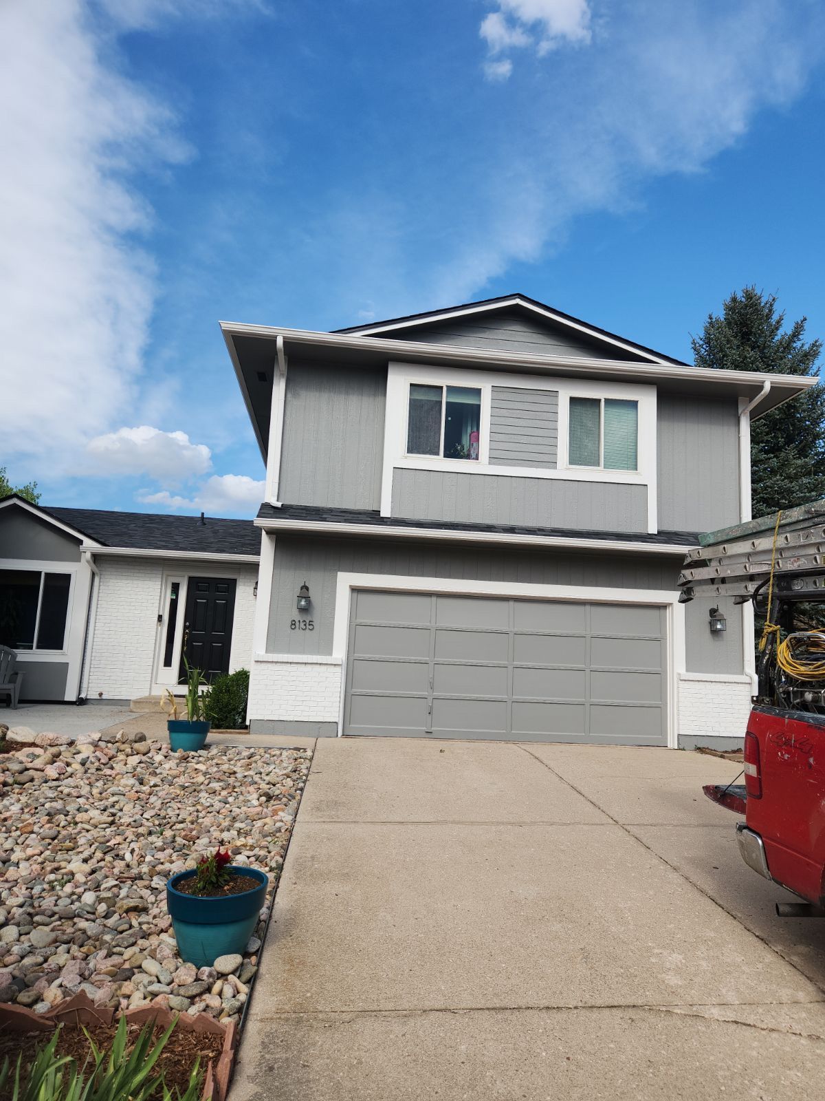Two-story suburban house with a double garage and driveway under a blue sky