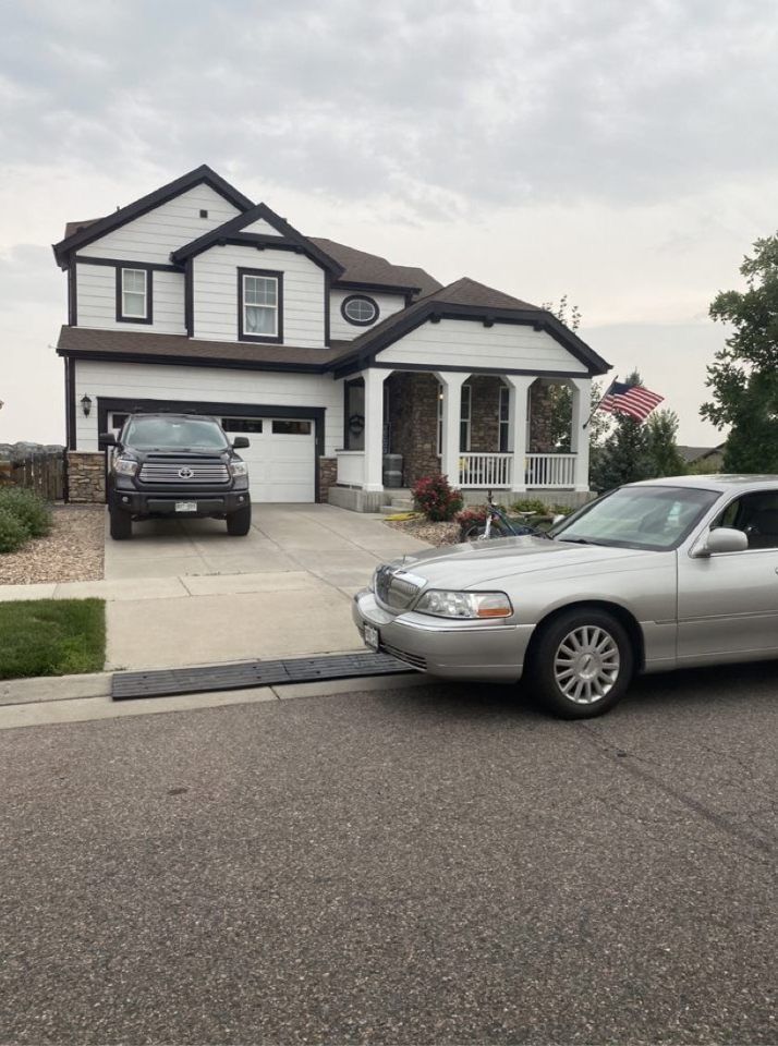 Suburban house with two parked cars and a curved driveway, viewed from the street