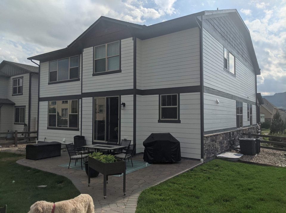 Two-story gray house with black trim and a small patio with outdoor furniture