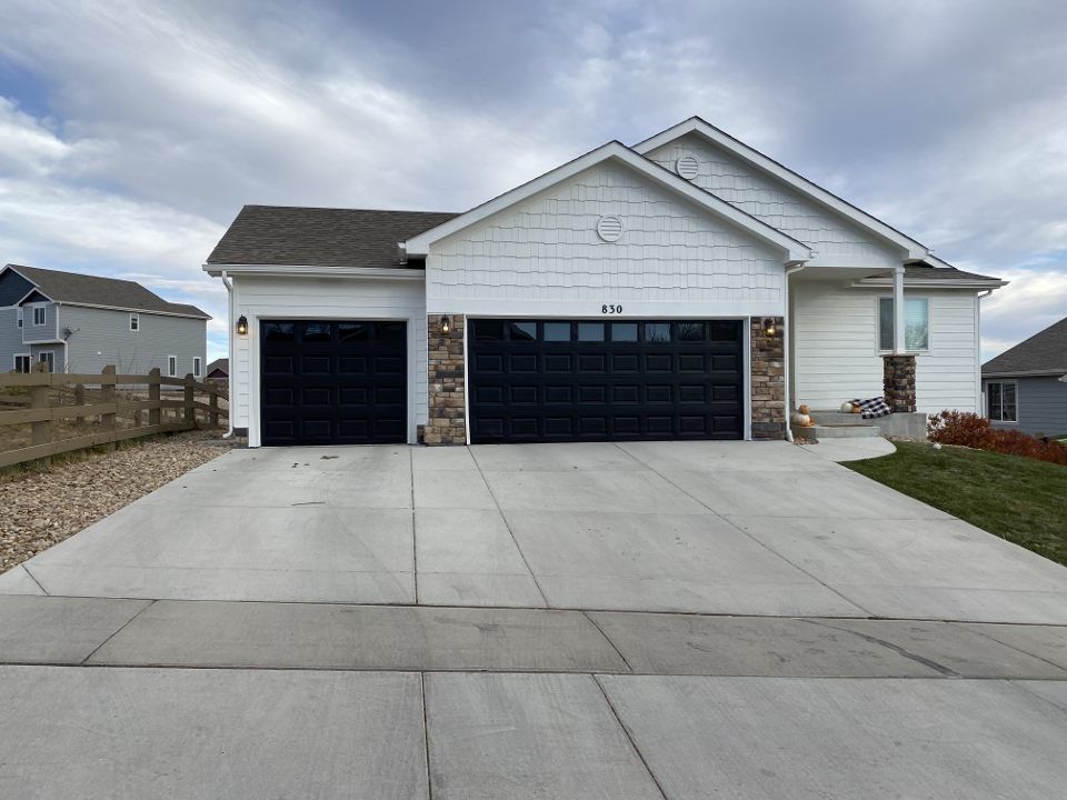 Suburban house with a two-car garage and concrete driveway under a cloudy sky