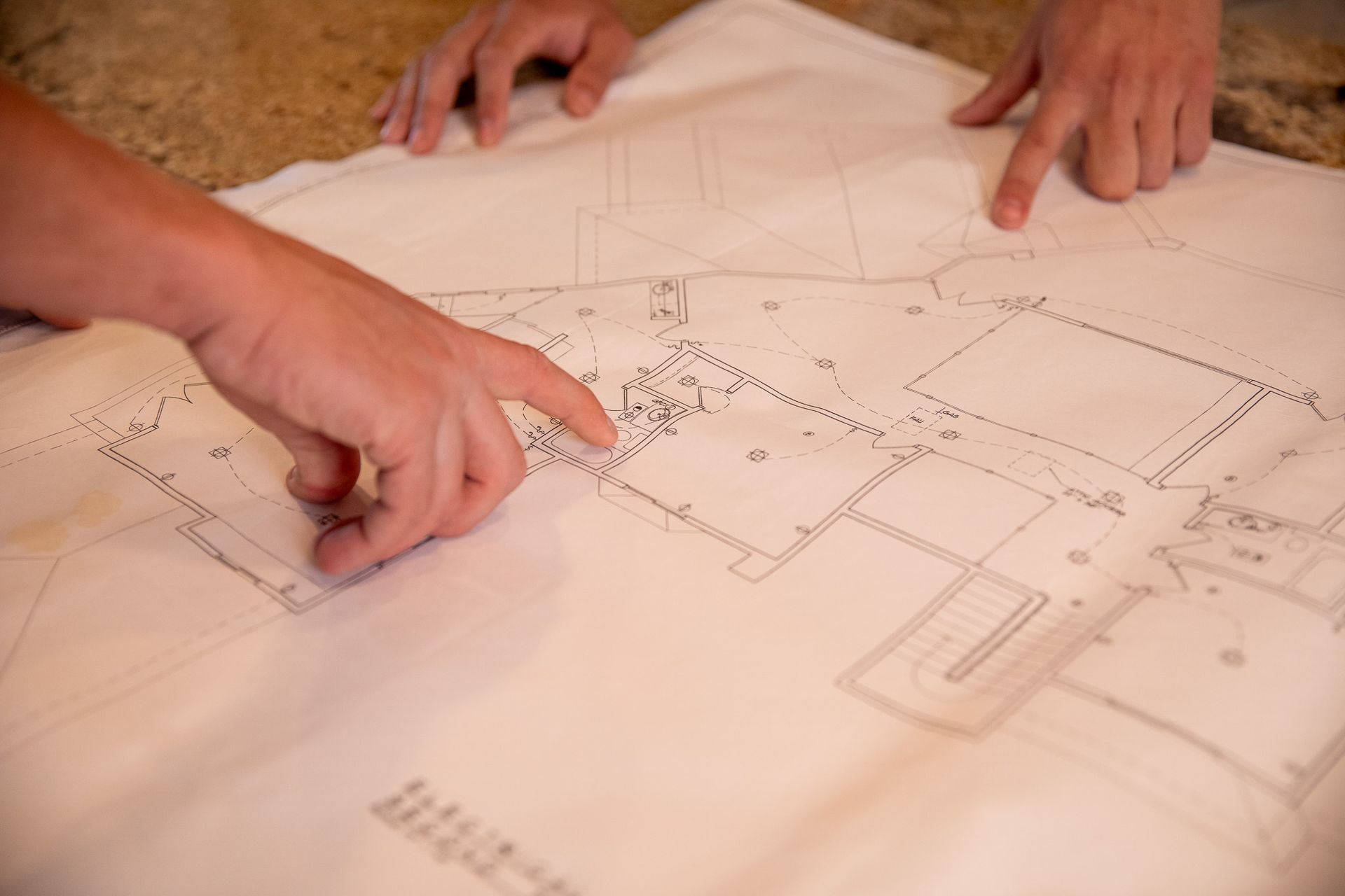 A person is pointing at a blueprint of a house.