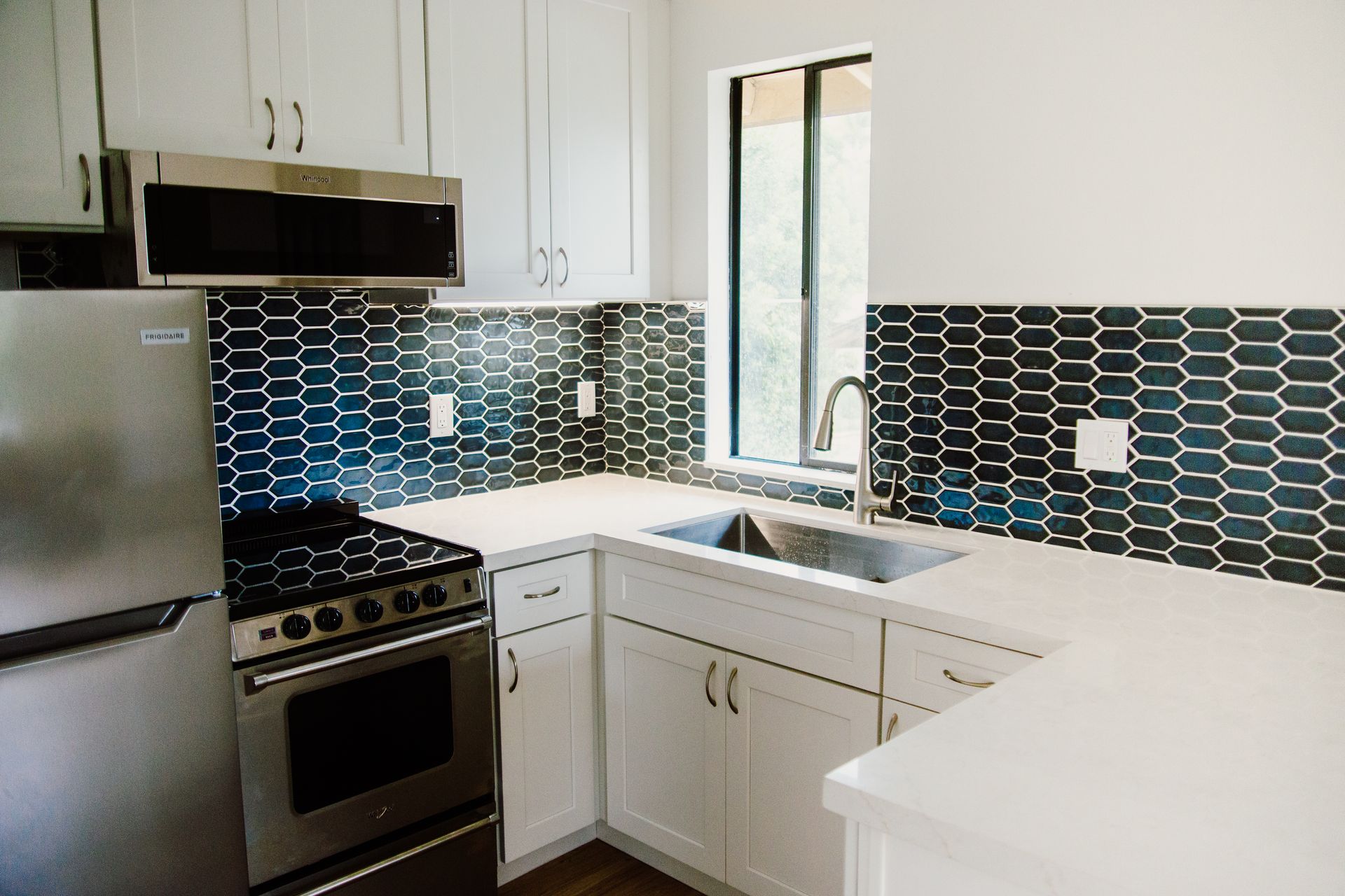 A remodeled ADU kitchen with stainless steel appliances and white cabinets