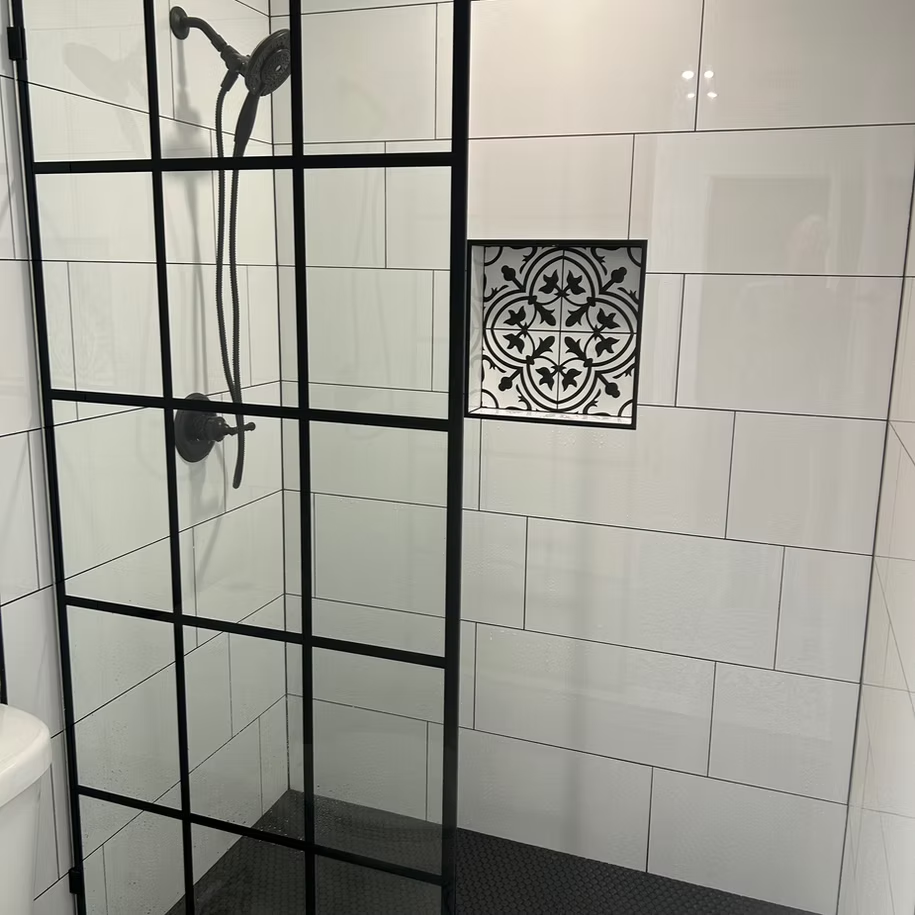 A remodeled shower with white tiles and a black frame.