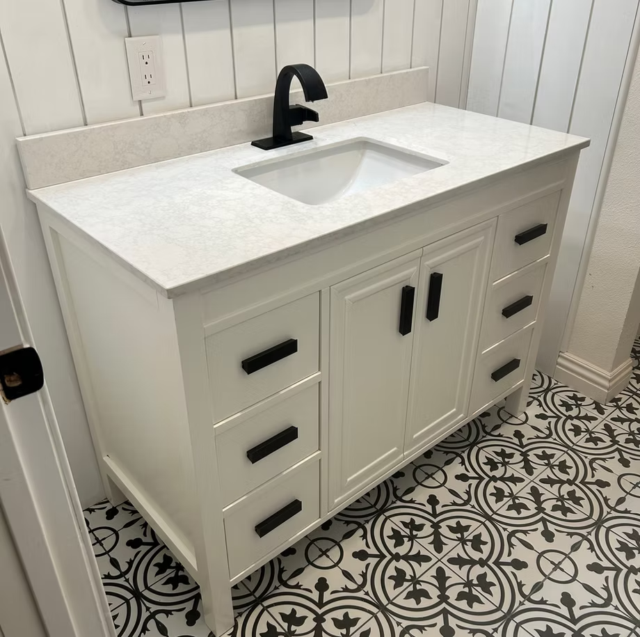 A bathroom vanity with a sink and a black faucet.