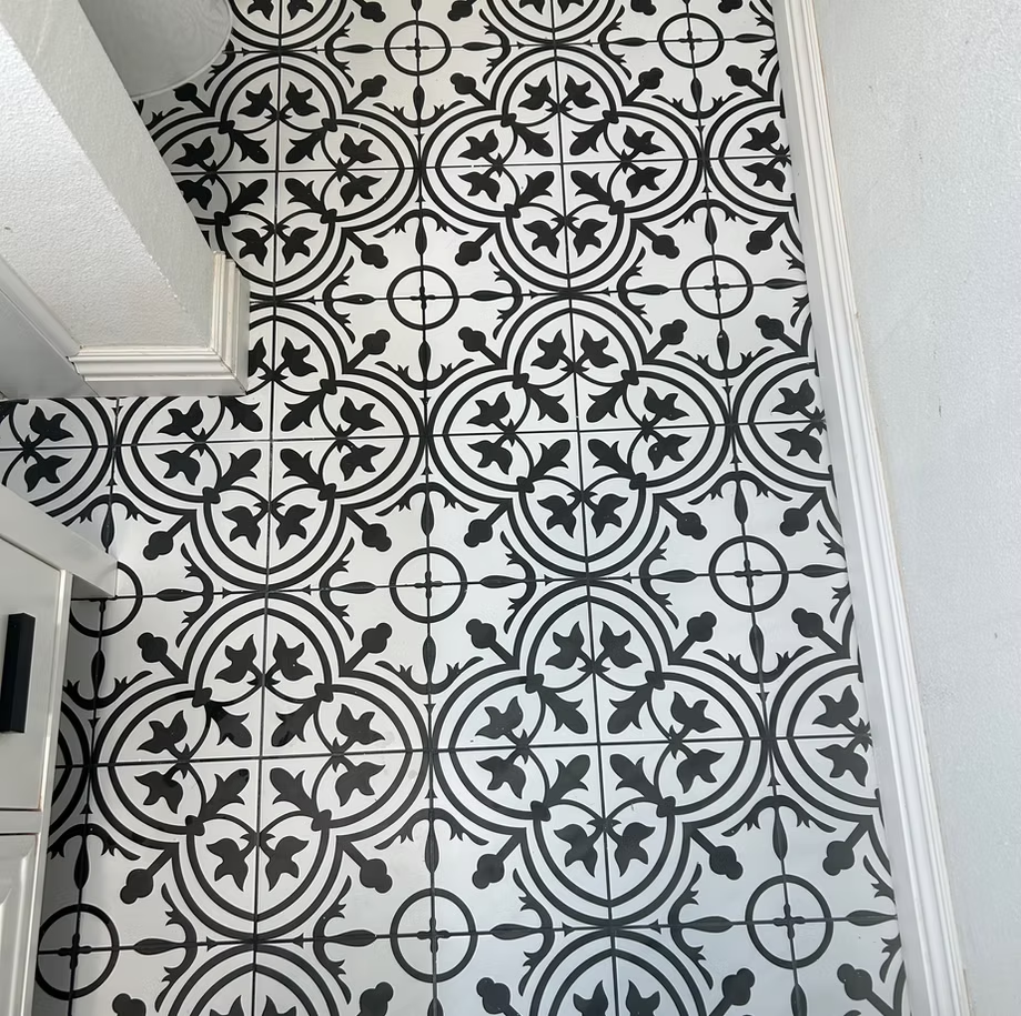 A black and white tile floor with a floral pattern in a remodeled bathroom.