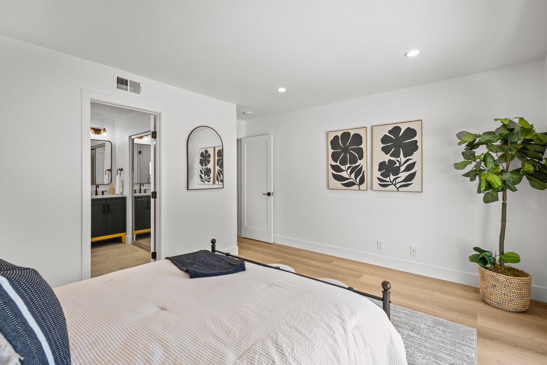 A remodeled bedroom with a large bed, wall mirror, and new modern doors.