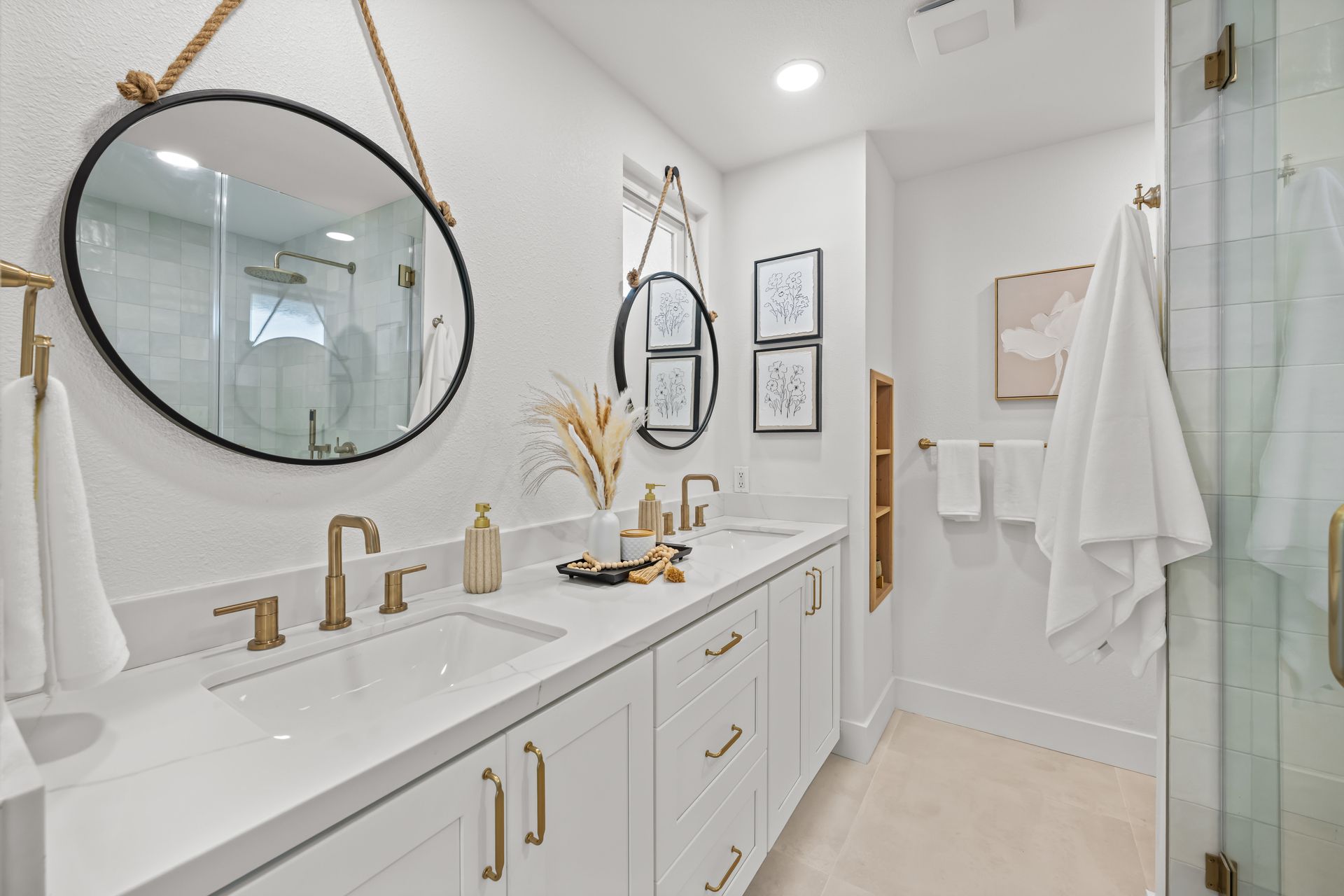 A modern remodeled bathroom with two sinks, a mirror and a walk in shower.