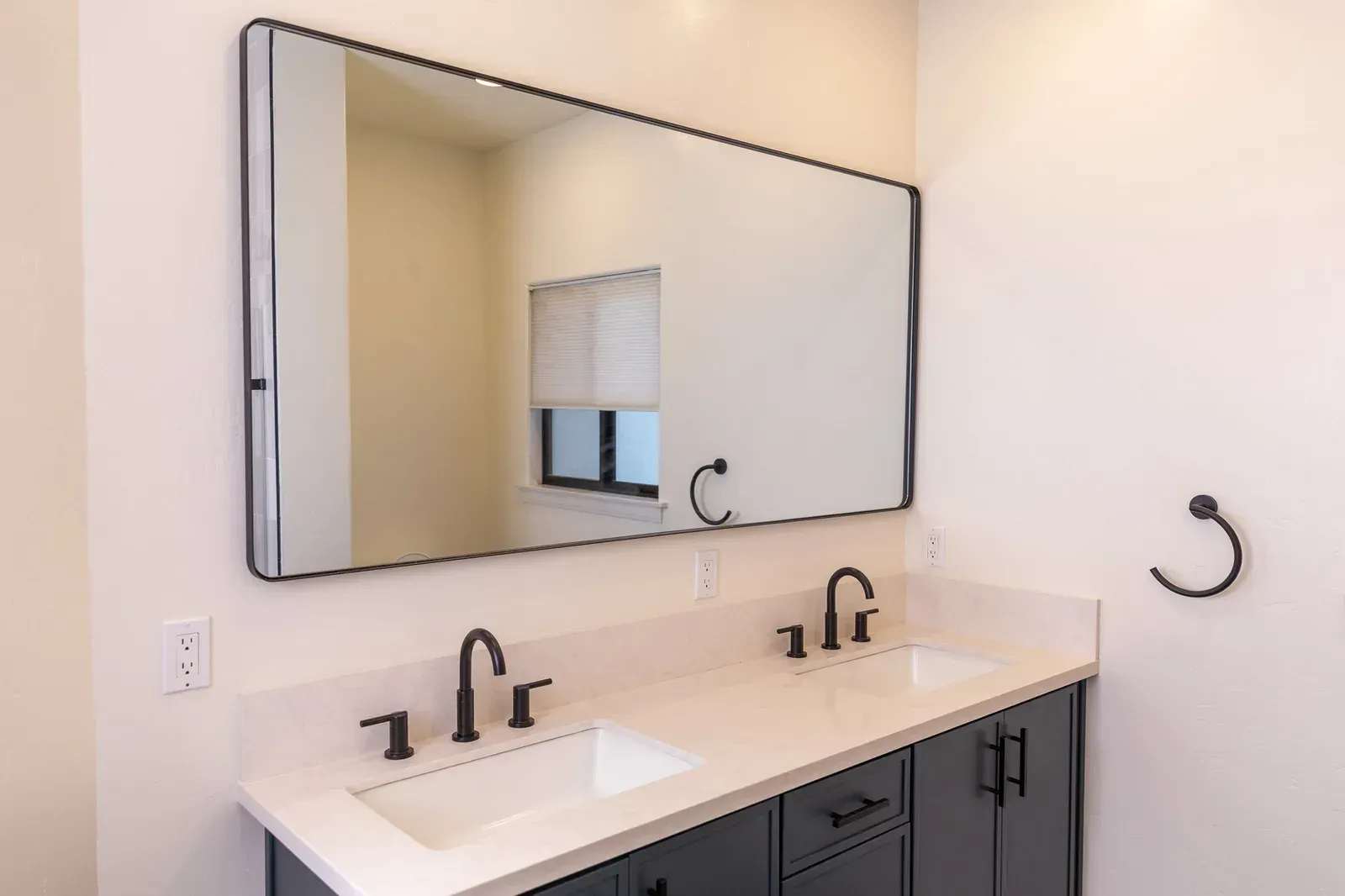 Modern bathroom vanity with double sinks, large mirror, and white countertop