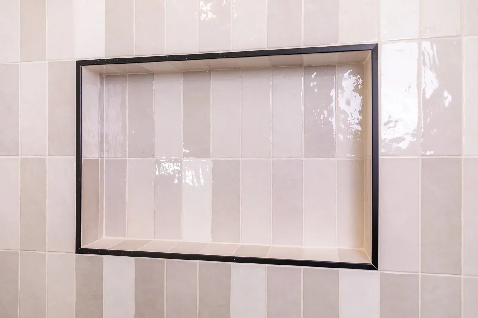 Built-in mirrored medicine cabinet set in a glossy white tiled wall