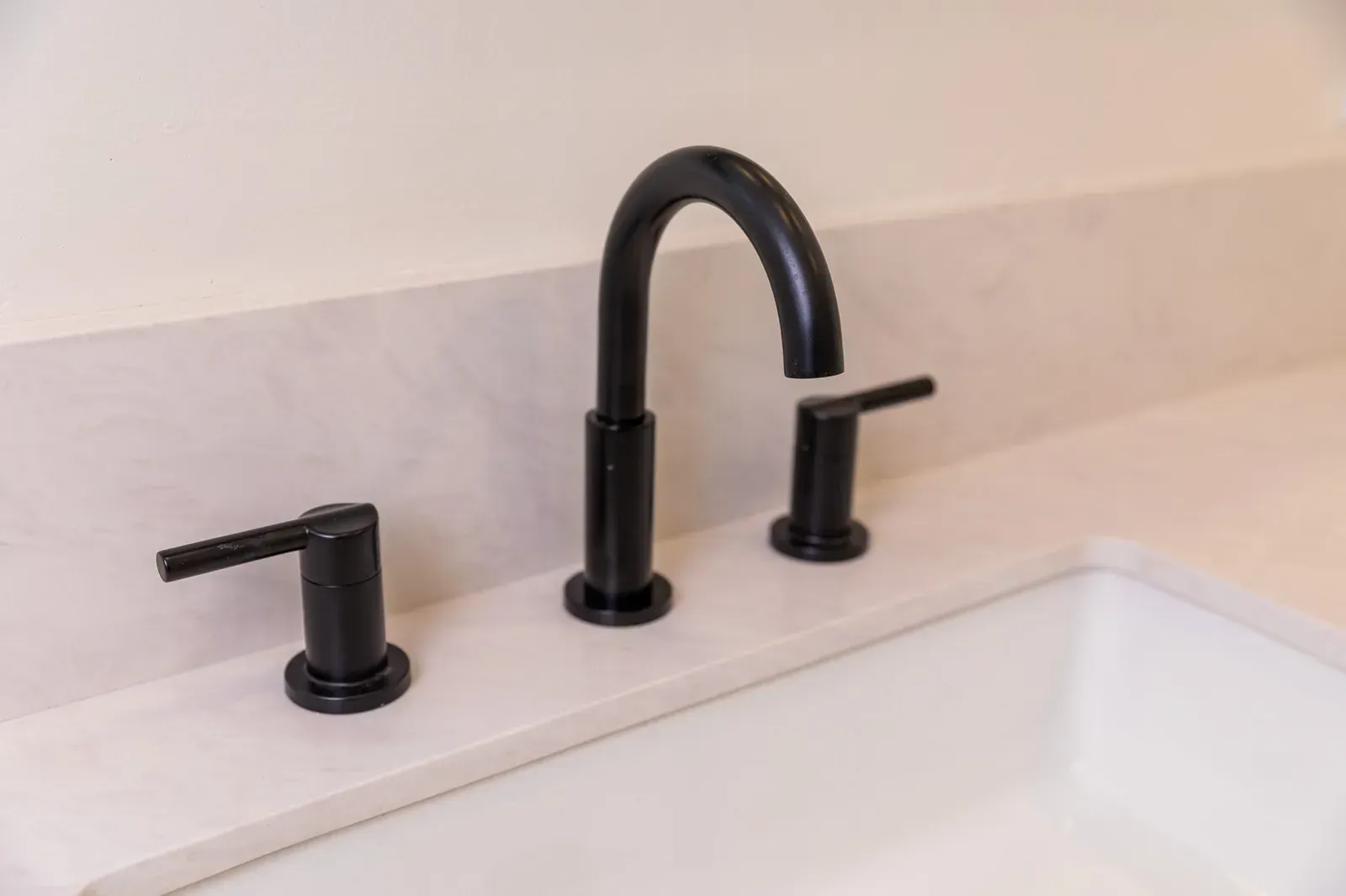 Black bathroom faucet and handles mounted on a white sink countertop