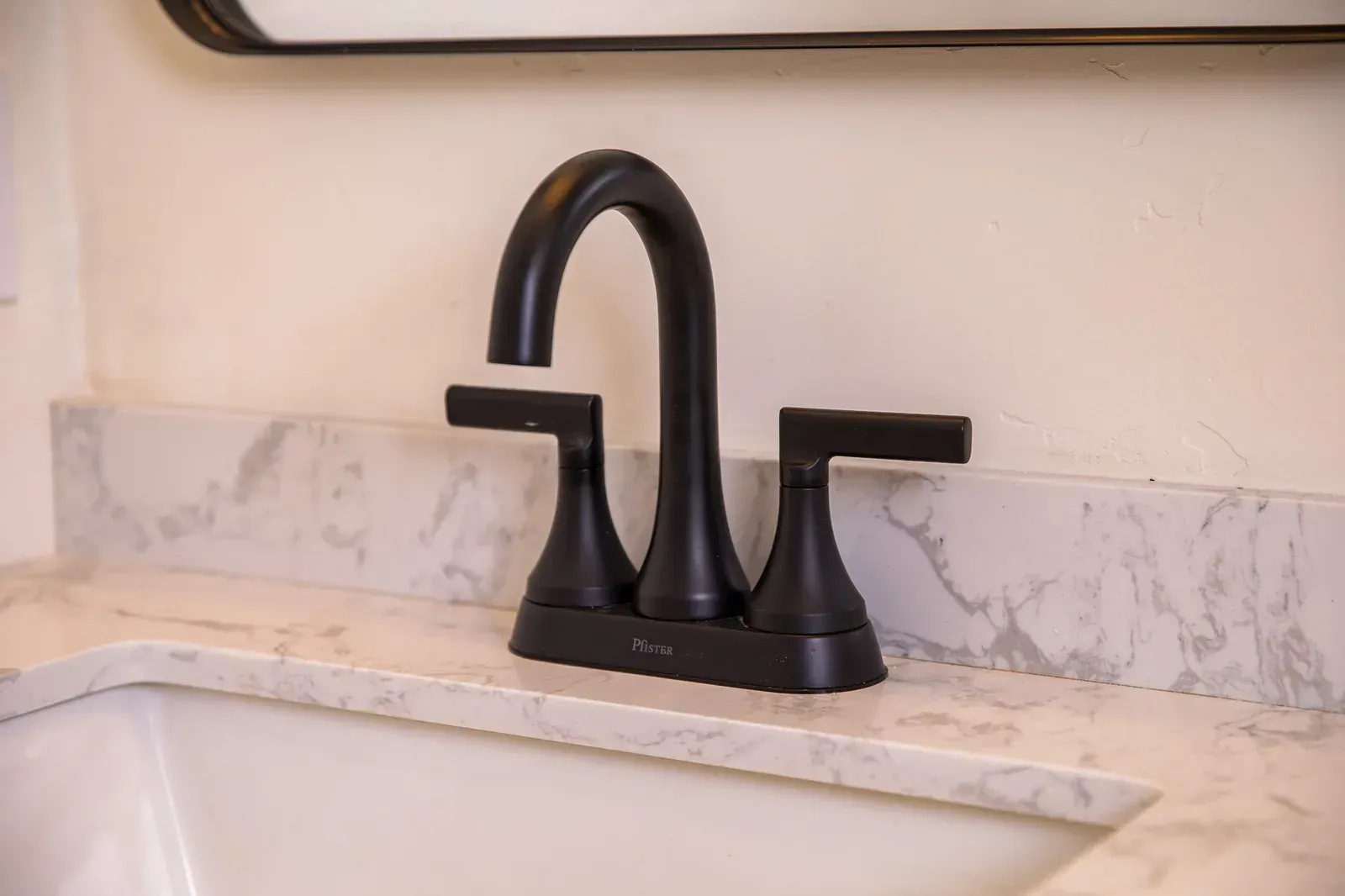 Matte black bathroom faucet with two handles over a marble sink countertop