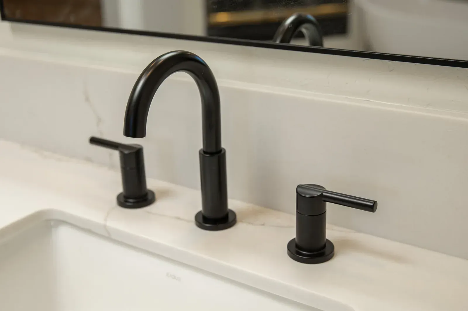 Black faucet and handle on a white bathroom sink countertop