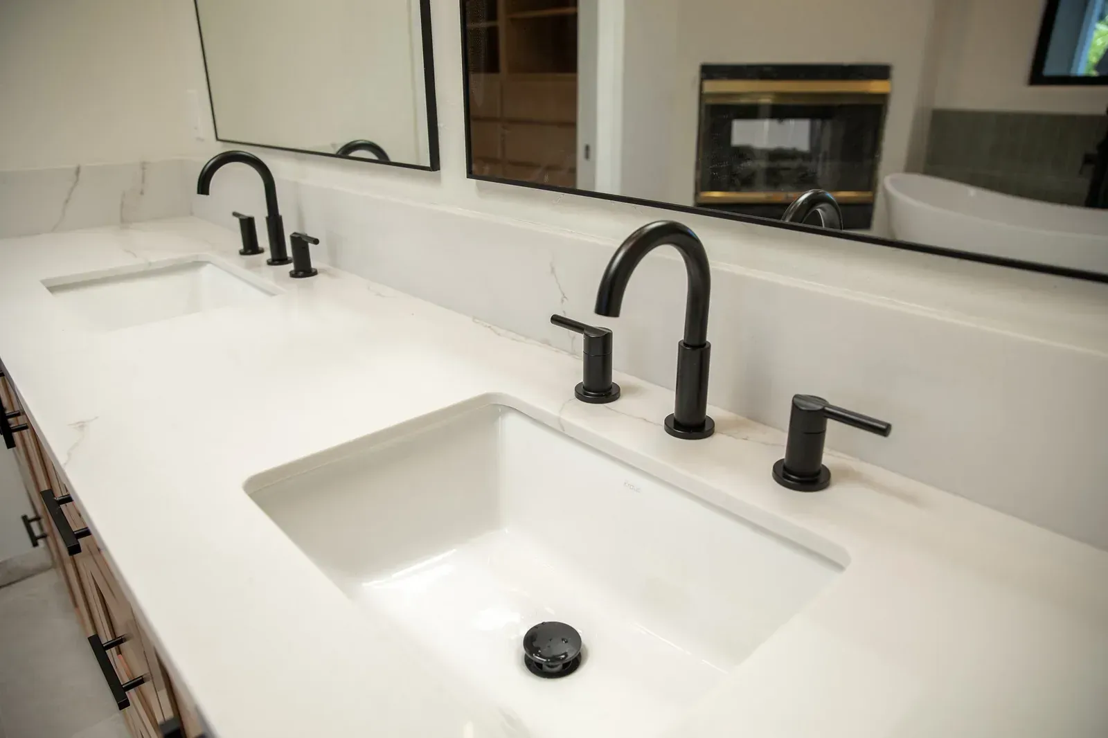 Modern bathroom double sink vanity with black faucets and a large wall mirror