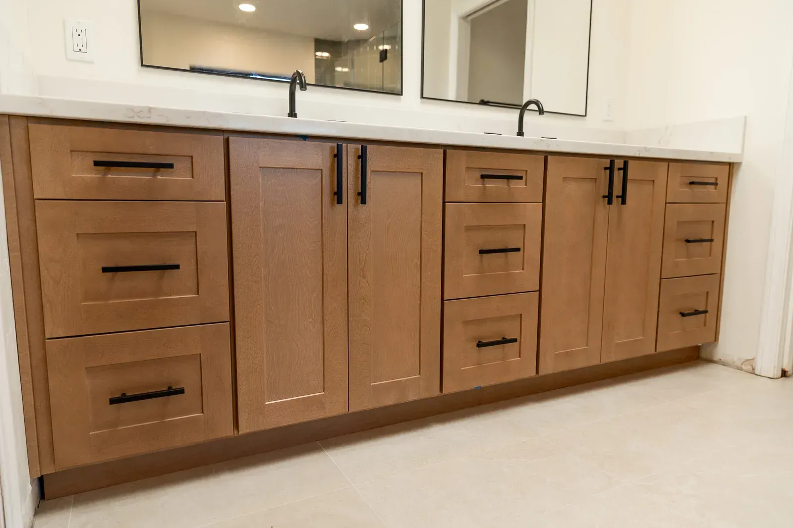 Wooden bathroom vanity with multiple drawers and cabinets beneath a white countertop and sink.