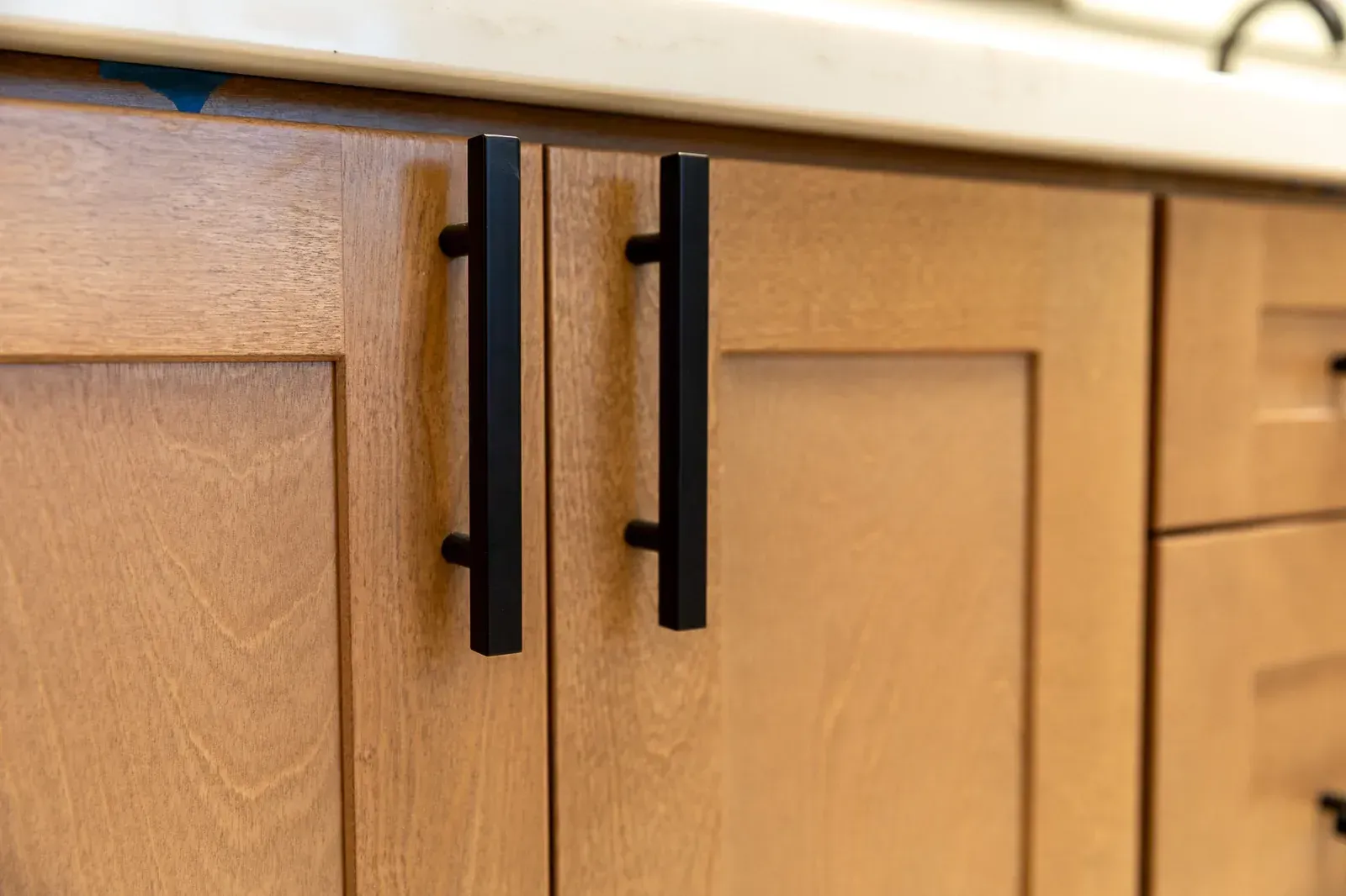 Black cabinet pulls on light wood kitchen cabinets