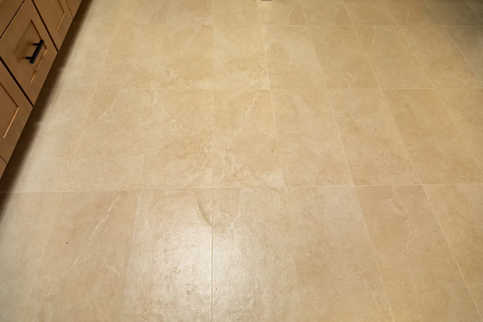 Beige tiled kitchen floor with wooden cabinets along the left edge