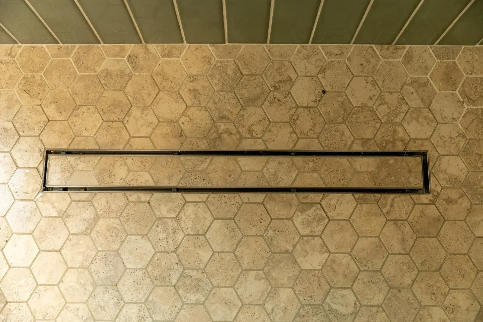 Long black wall-mounted rectangular light on a beige hexagonal tile wall