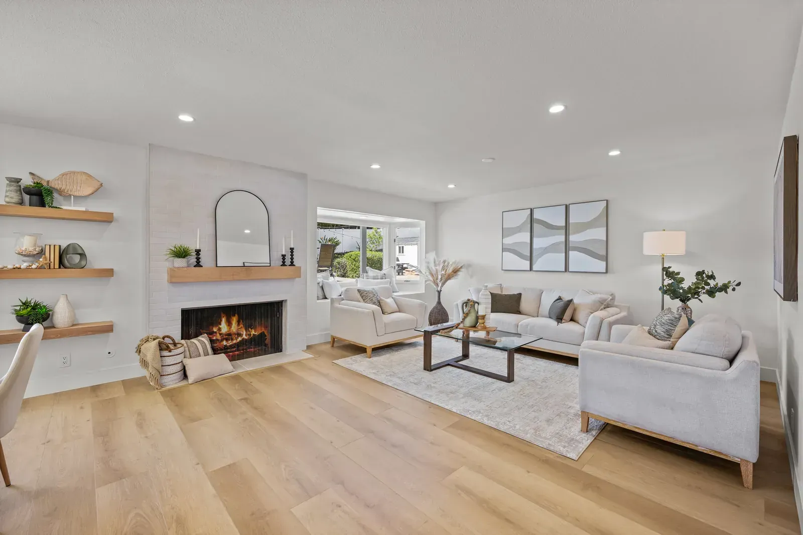 Bright modern living room with white sofa, fireplace, wood floors, and recessed ceiling lights