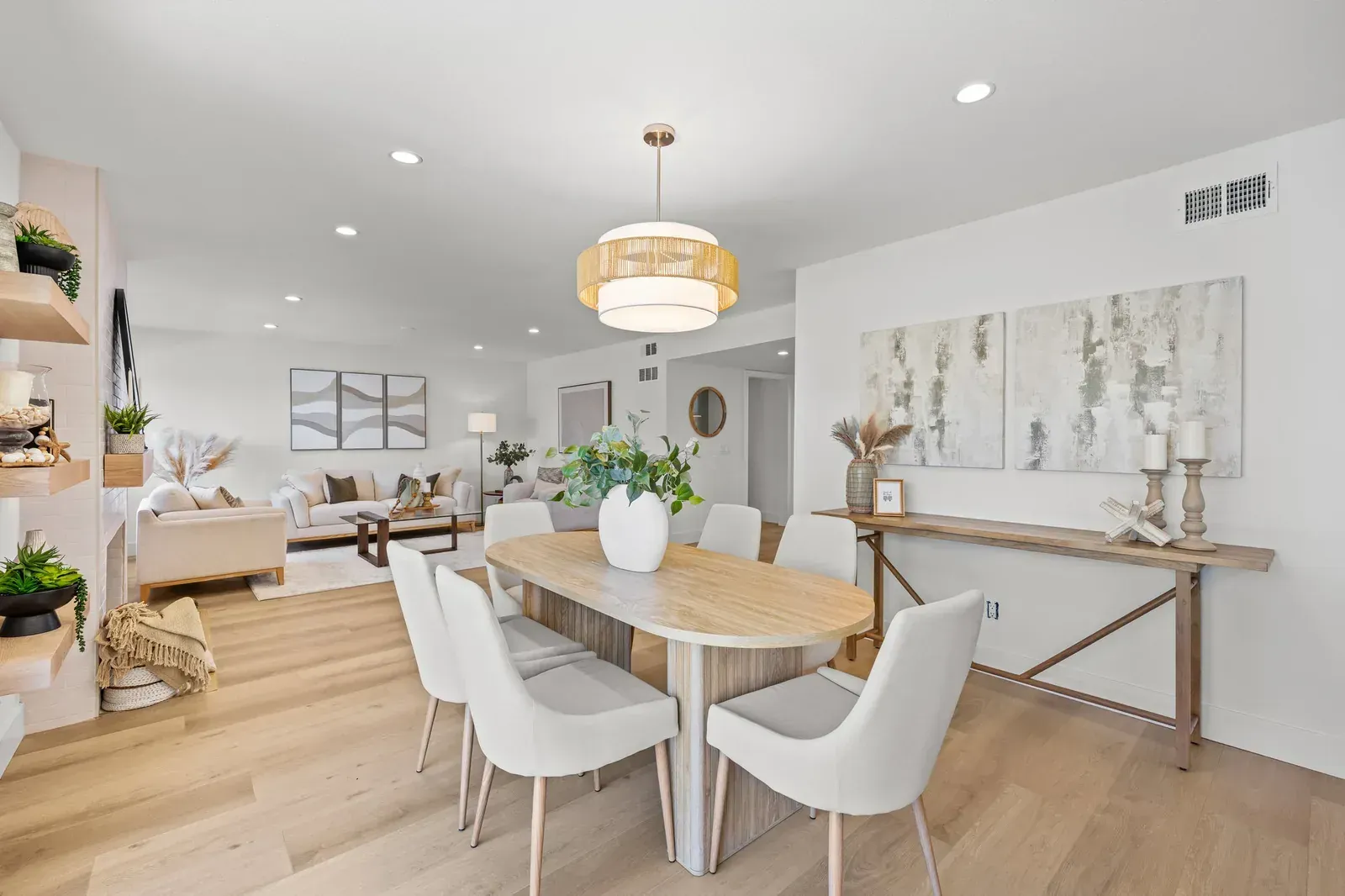 Bright modern dining room with a wooden table, white chairs, pendant light, and neutral decor