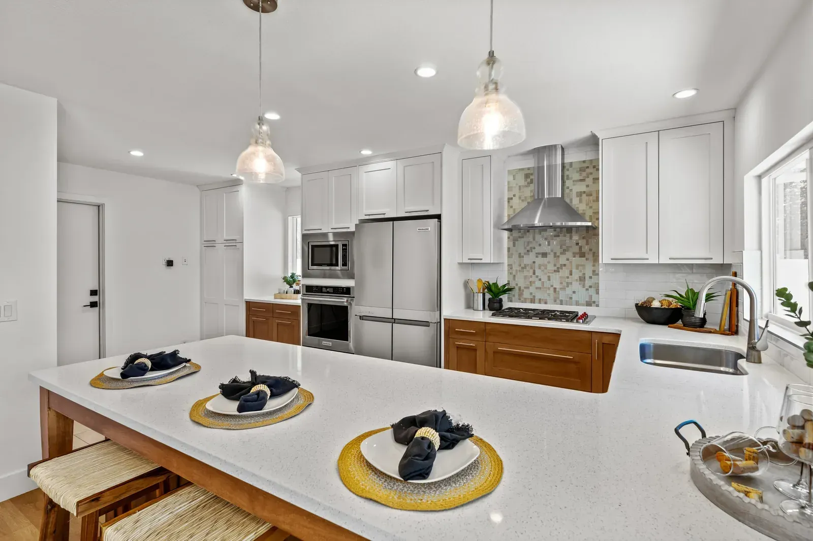 Bright modern kitchen with white cabinets, island, pendant lights, and stainless steel appliances
