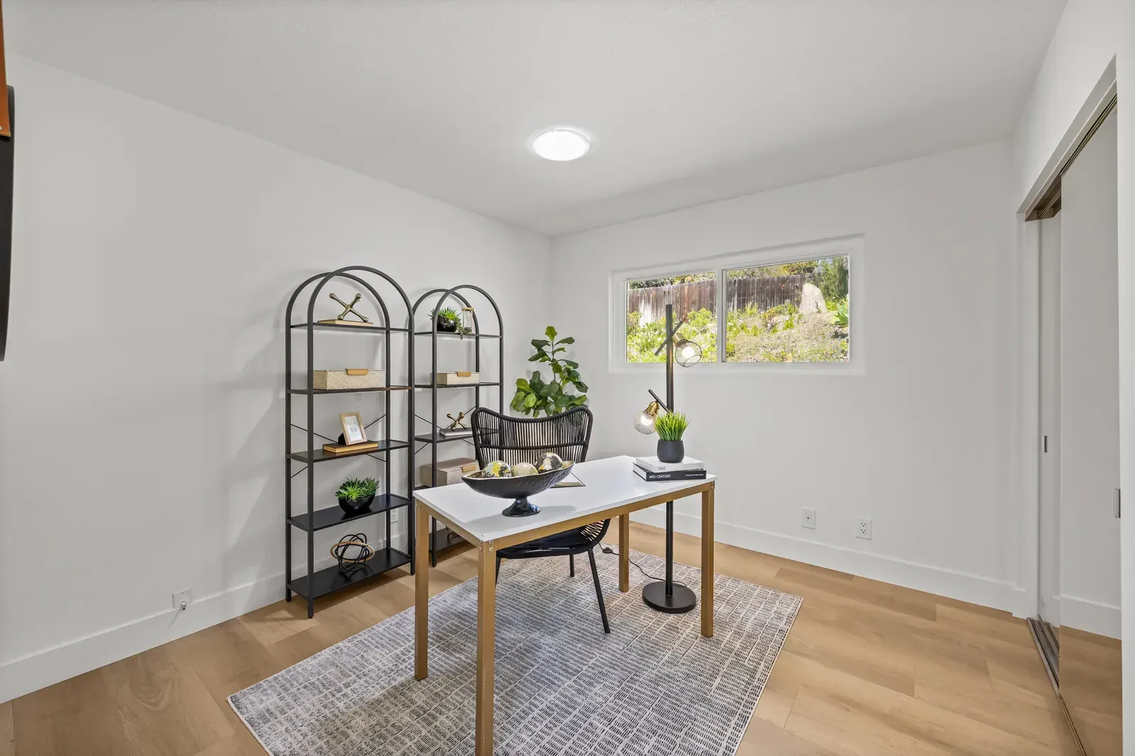 Bright home office with a desk, chairs, shelves, rug, and a small window.