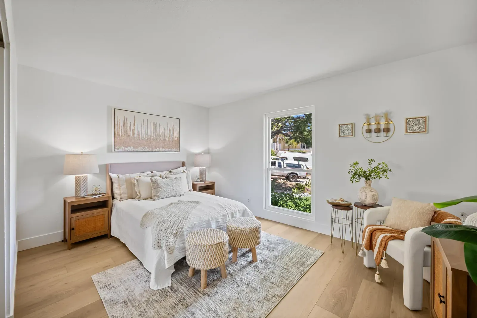 Bright modern bedroom with a bed, nightstands, rug, chair, and large window