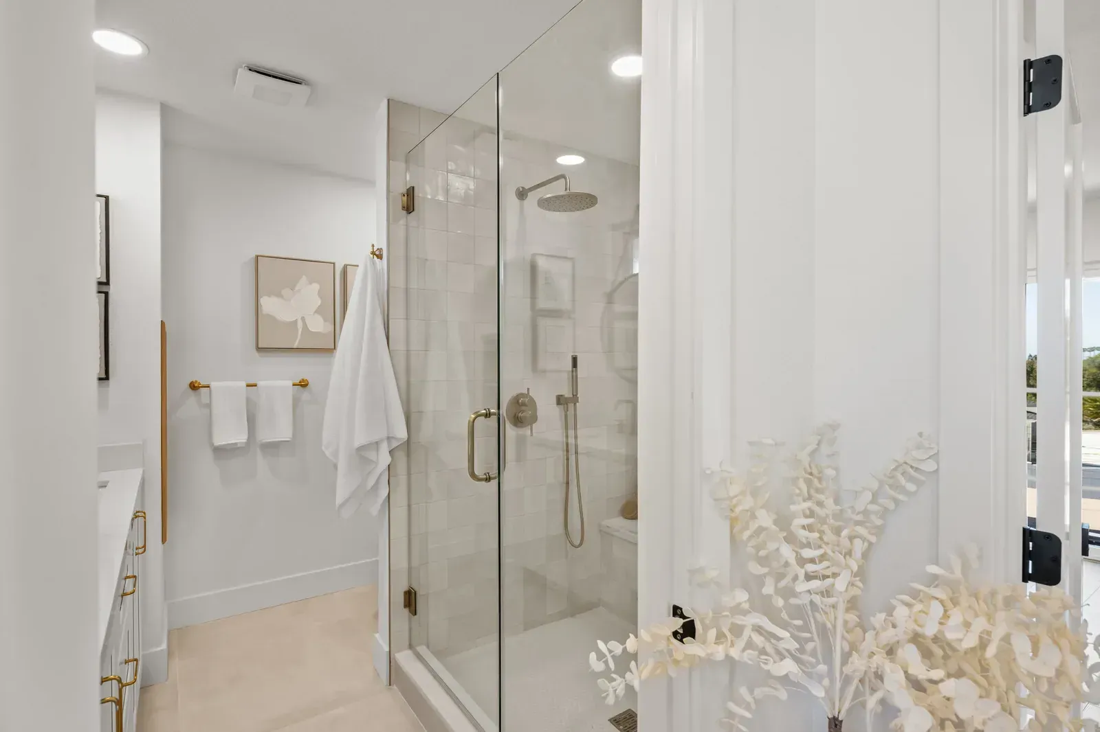 Bright modern bathroom with glass shower, white towels, and neutral decor