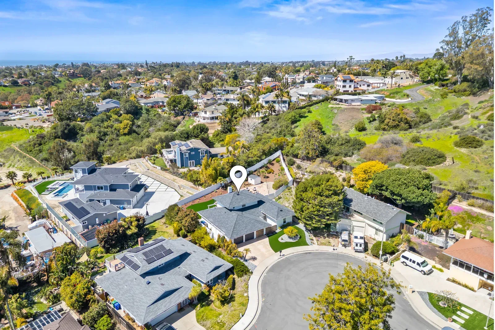 Aerial view of a suburban neighborhood with homes, trees, and winding streets on a sunny day