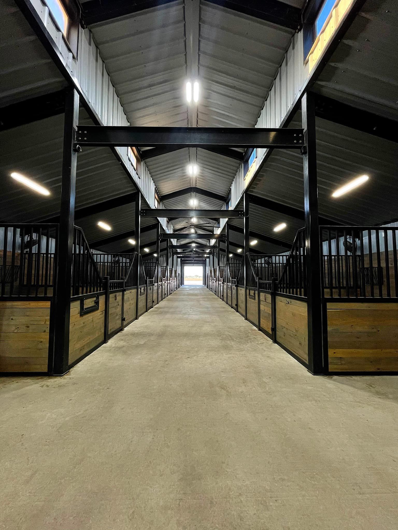 A long hallway filled with rows of horse stables.