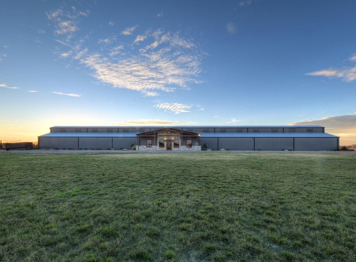 A large building is sitting in the middle of a grassy field.