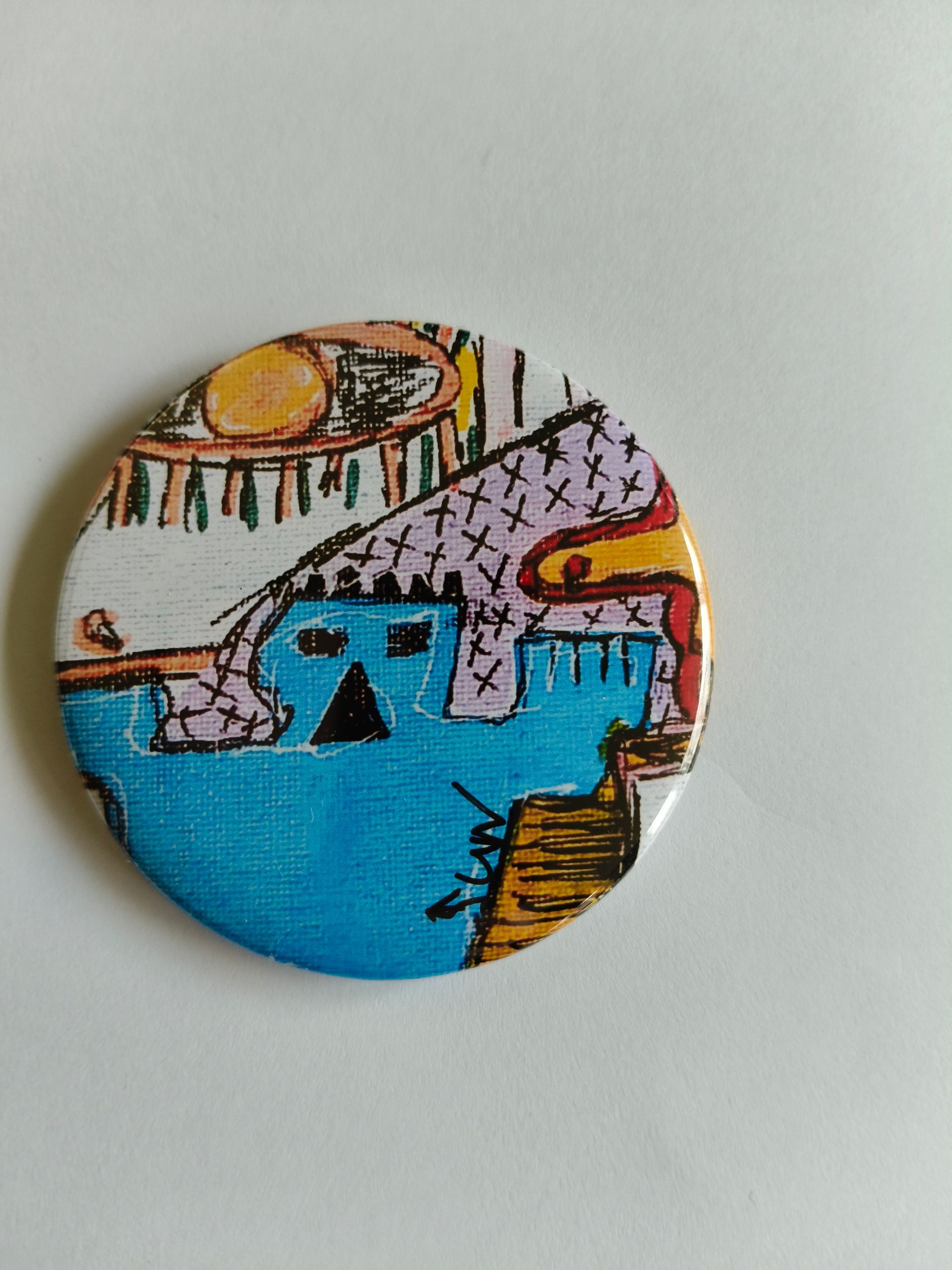 Een ronde button met een gestileerde tekening van een blauwe man, een oranje zon en paarse patronen op een witte achtergrond.