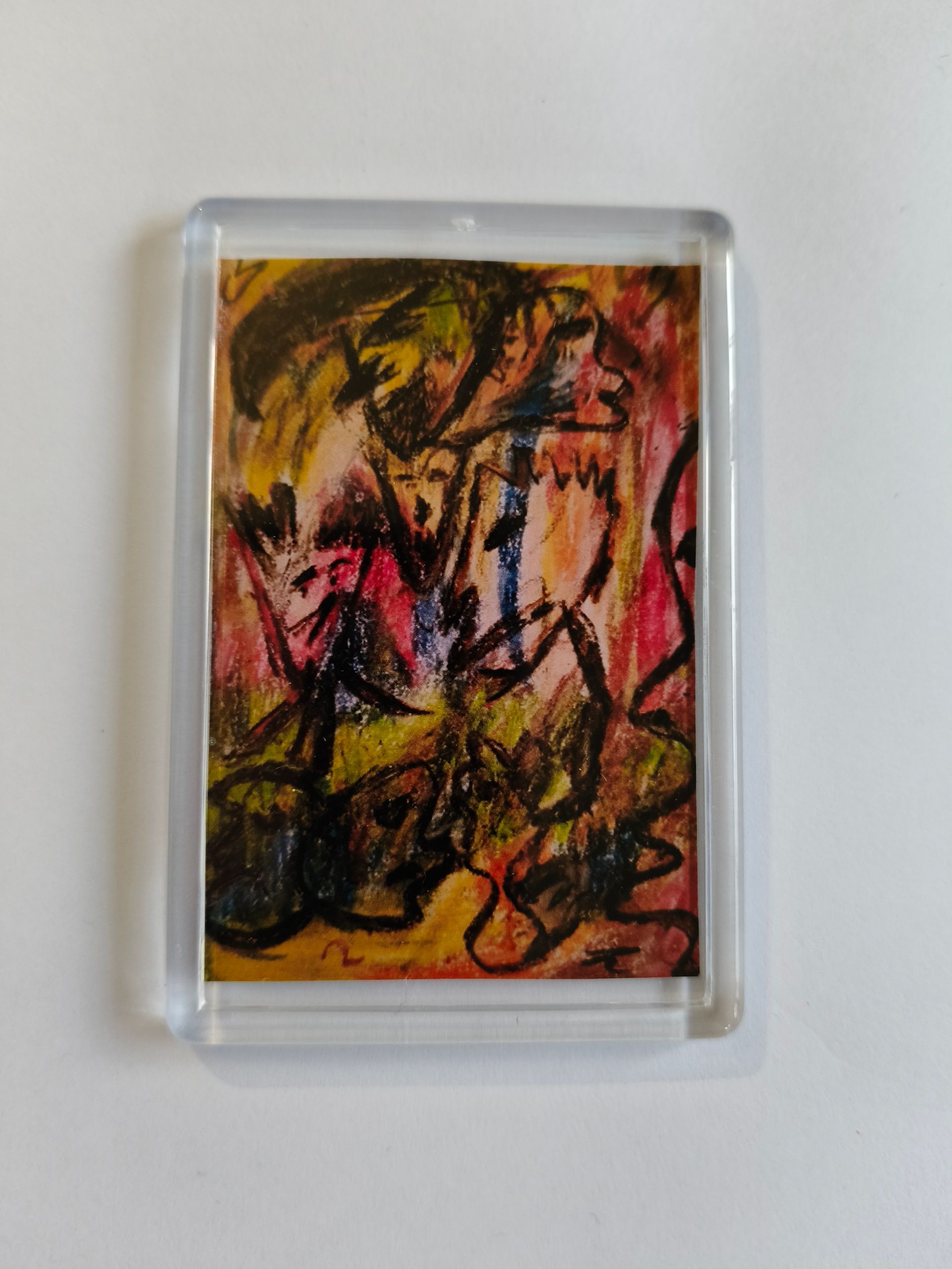 koelkast magneet van een abstracte, expressionistische tekening met chaotische zwarte lijnen over vlekken rood en geel.